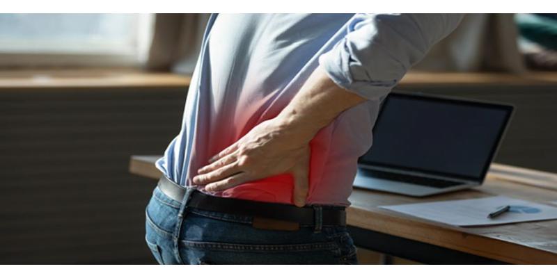 Close up rear view stressed young man touching lower back feeling discomfort, suffering from sudden pain due to sedentary lifestyle or long computer overwork in incorrect posture at home office.